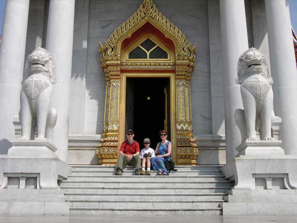 Bangkok 02 04 Wat Benchamabophit Marble Wat Posing at Entrance We decided to get into the same mood, with a team photo. We paused for a few minutes to enjoy the beautiful white marble of the Wat Benchamabophit, with a pair of white marble singhas (mythical lions) framing the stairs.